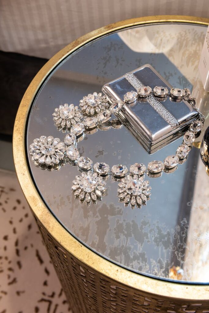 From above of silver necklace with floral ornament and diamonds on metal box on table in house room